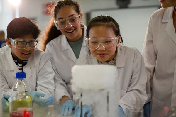 ​​Young students watching a chemical reaction in a science experiment in the classroom​ 